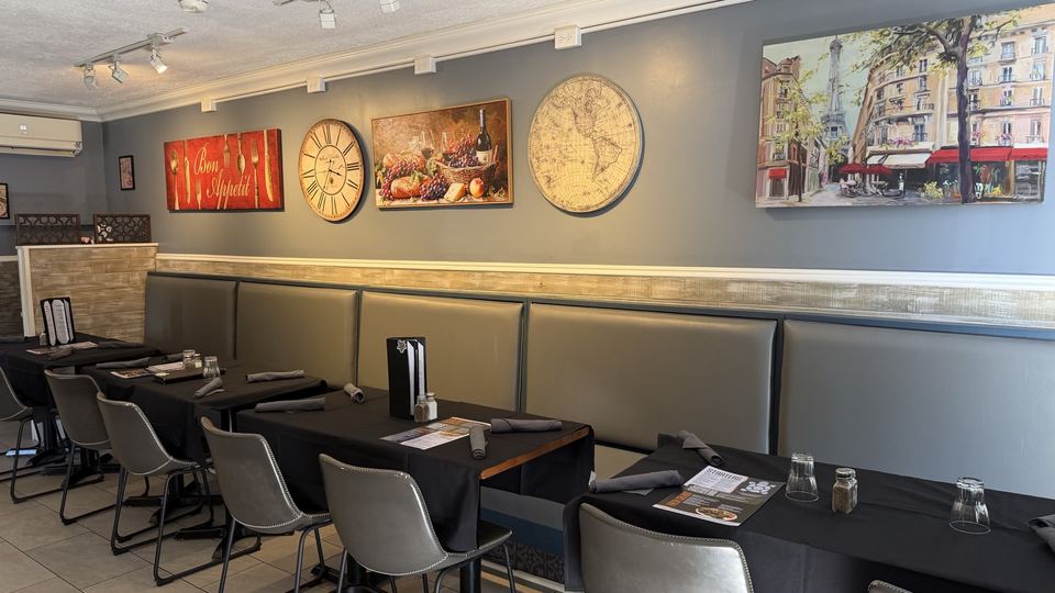 The dining room banquette running the length of the grey wall under framed prints.
