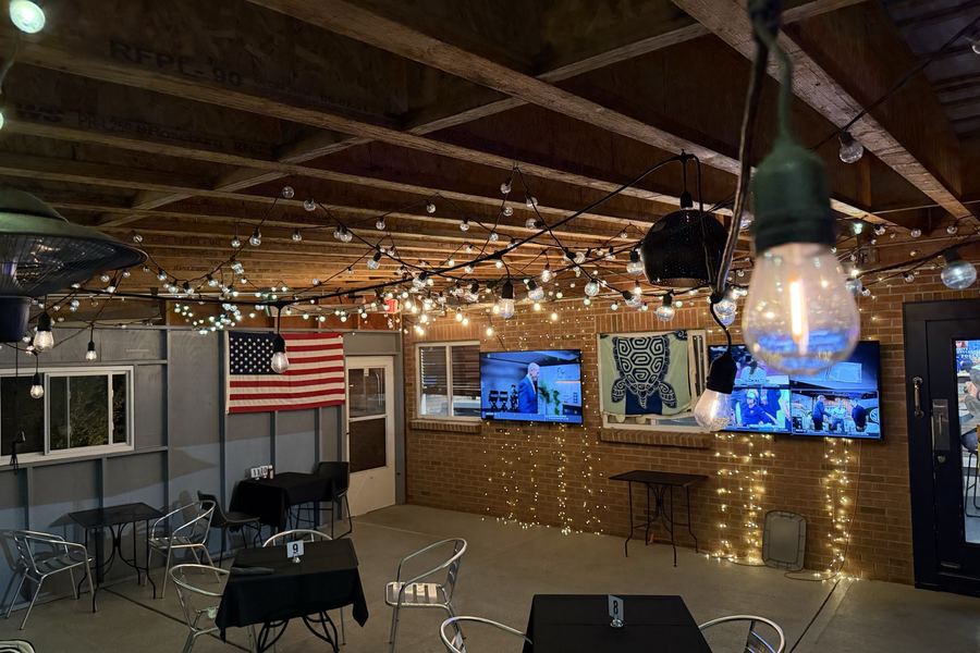 The covered patio strung with lights, tables set for the evening.