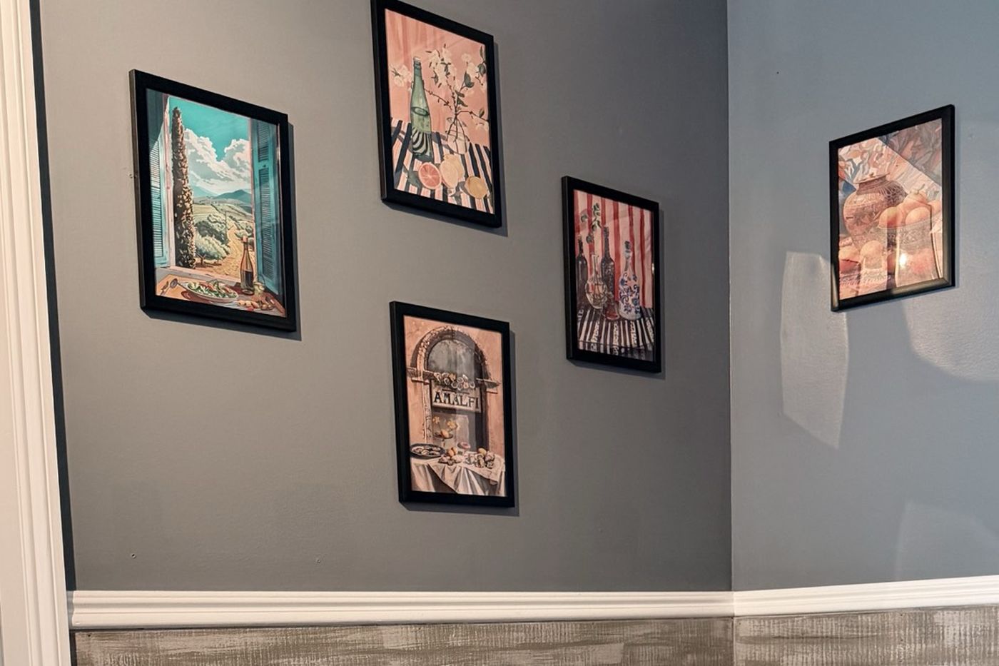 Five framed Mediterranean still-life prints arranged on a grey wall.