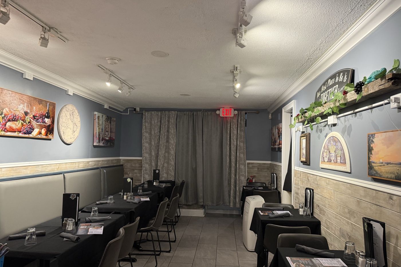 The dining room set for service, tables in black linen under warm light.